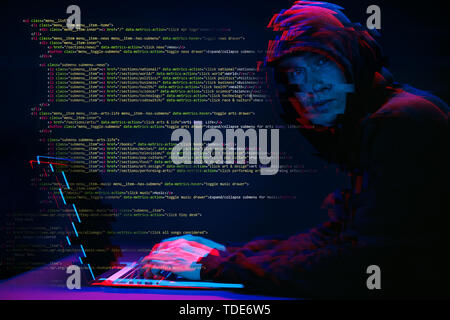 Hacker working with laptop in dark room with digital interface around. Image with glitch effect. Stock Photo