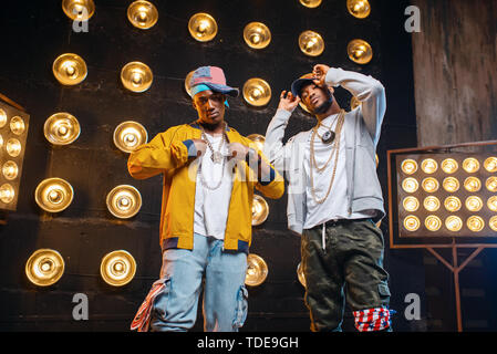 Black rappers in caps on stage with spotlights Stock Photo