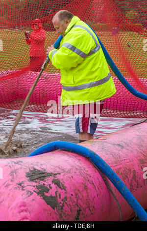 Baiter Park, Poole, Dorset, UK. 15th June 2019. Cold wet day for Race for Life Pretty Muddy. Preparing the mud pool to ensure participants get covered in mud glorious mud! Filling with hose. Credit: Carolyn Jenkins/Alamy Live News Stock Photo