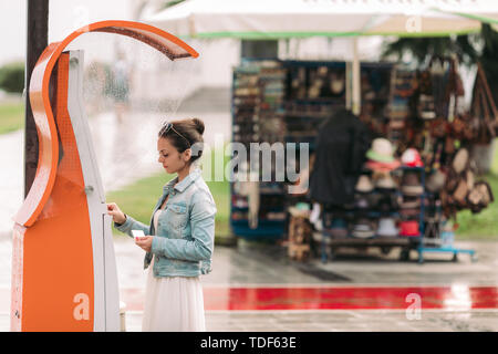 Tourist woman buys tickets for transport in Georgia. modern street machine for purchase of tickets for bus Stock Photo