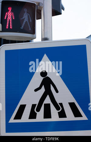 Crosswalk road sign. Pedestrian crossing sign and traffic light for pedestrians. Red light no passage. Standing man glows red at the traffic lights. Stock Photo