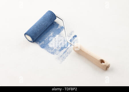 Sponge roller with blue paint on white wallpaper background Stock Photo