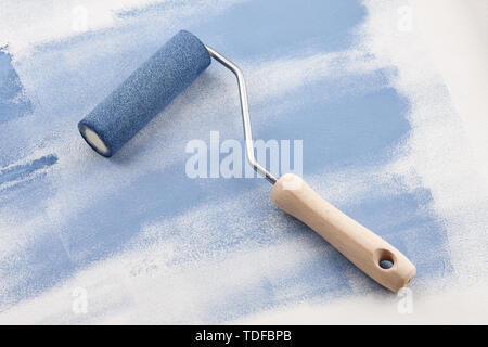 Sponge roller with blue paint on white wallpaper background Stock Photo