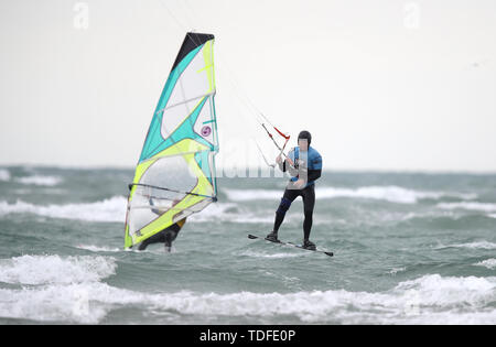 A kite surfer and wind surfer take advantage of the strong winds off of West Wittering beach in West Sussex. Stock Photo