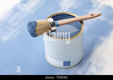 Brush and can of blue paint on painted surface with strokes Stock Photo