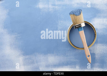 Brush and can of blue paint on painted surface with strokes, top view Stock Photo