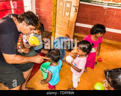 PUDUCHERY, INDIA - DECEMBER Circa, 2018. Poor preschool teacher and her group of kids boys girls having some fun at school with just a few wood toys g Stock Photo