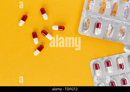 blister packaging of red and white capsules on a yellow background Stock Photo
