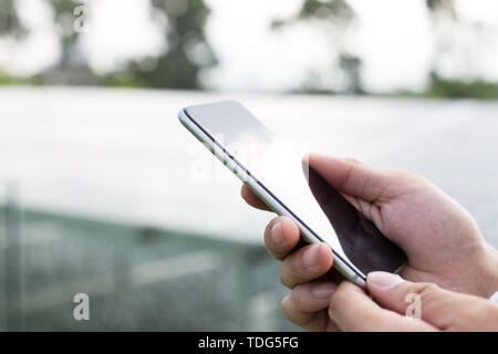 Hand with mobile phone outdoors Stock Photo