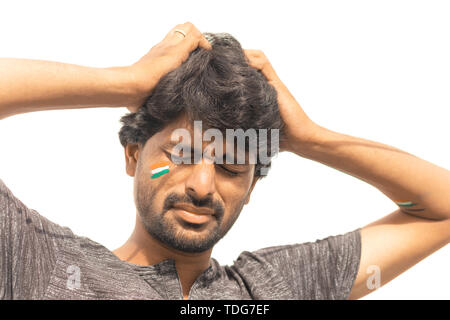 Closeup Shot, Sad expression of Male Indian Cricket sport fan with painted Indian flag on face, isolated background Stock Photo