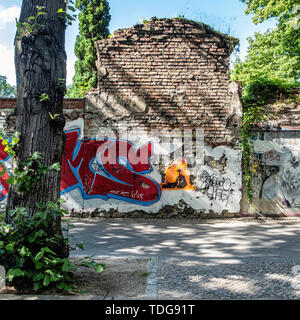 Graffiti-covered Cemetery wall with exposed brickwork & street art in Baruther strasse, Kreuzberg-Berlin Stock Photo