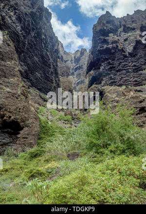 Rocks in the Masca gorge, Tenerife, showing solidified volcanic lava flow layers and arch formation. The ravine or barranco leads down to the ocean fr Stock Photo