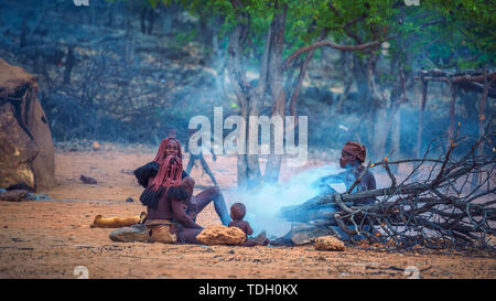 People of the Himba tribe sitting around fire in their village Stock Photo