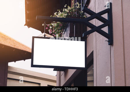 Empty signage and blank mock up hanging on street with copy space Stock Photo