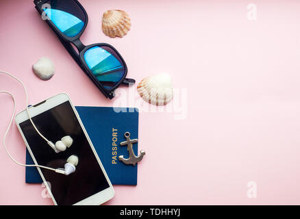Travel vacation concept flat lay, space for text. Traveler stuff including passport, phone, earphones, sunglasses against pink background. Stock Photo