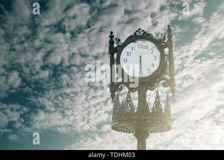 Vintage analogue clock against sunset with beautiful clouds Stock Photo