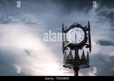 Vintage analogue clock against sunset with beautiful clouds Stock Photo