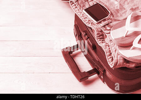 Open suitcase with travel accessories on white wooden table with copyspace. Stock Photo