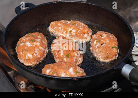 Delicious wild red salmon fish cutlets fried in hot griddle roast on coals, over open fire on campfire. Cooking food on fire during picnic on sunny su Stock Photo