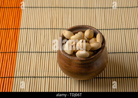 Nuts. Pistachios in a clay bowl on the table. Top view Stock Photo