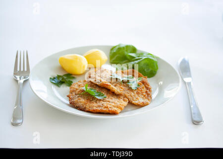 Two fried fish fillet from the flatfish flounder with potatoes, spinach and flat leaf parsley with cutlery. Stock Photo