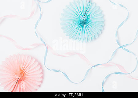 Abstract pastel white background of paper party decorations and silk ribbons of pink and blue color, flat lay. Stock Photo