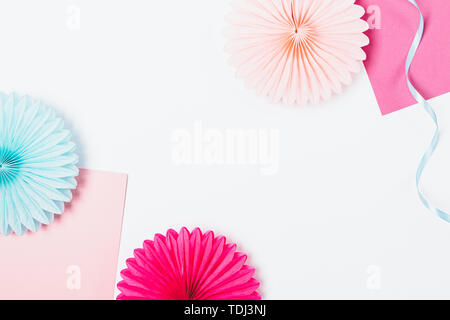 Flat lay frame of paper party decorations of pink and blue colors on white background with free space in center. Stock Photo