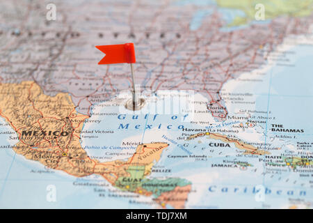 Small red flag marking the Gulk of Mexico on a world map. Stock Photo