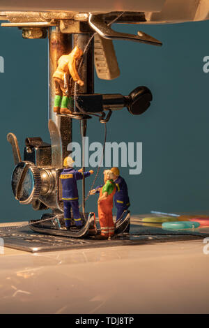 miniature people change thread on sewing machine. Stock Photo