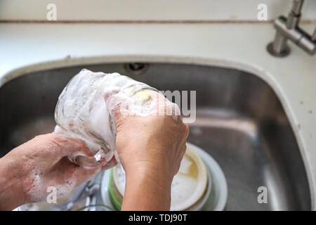 A woman cleaning kitchenware  in the sink. Stock Photo