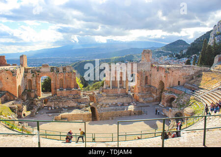 Taormina, Sicily, Italy - Apr 8th 2019: Beautiful ancient theatre of Taormina. Ancient Greek theatre, ruins of significant landmark. Amazing view of Etna volcano from the auditorium. Stock Photo