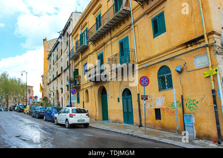 Palermo, Sicily, Italy - Apr 11th 2019: Generic street in Sicilian Palermo. Parking cars, buildings with graffiti. Dirty city streets. Italian cities. Road signs. Stock Photo