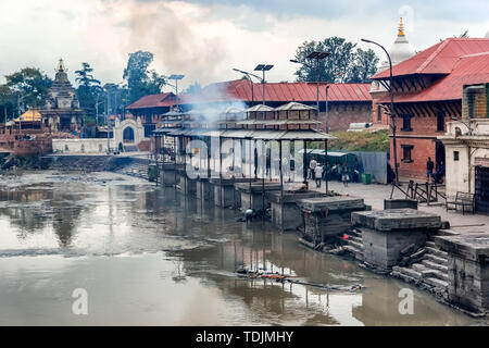 Kathmandu, Nepal - Oct 12, 2018: Friends and family watching cremation of a dead body  at Bagmati River near Pashupatinath Hindu Temple in Kathmandu,  Stock Photo