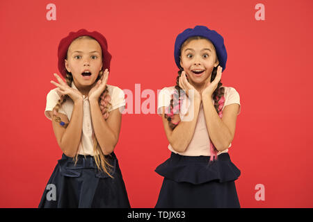 School fashion concept. Surprised girls wear formal uniform red background. International exchange school program. Education abroad. Apply form enter international school. French language school. Stock Photo