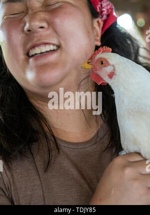 Perryville, Arkansas - Emily Koltes, a volunteer at Heifer Ranch, holds a chicken. Heifer Ranch is a 1,200-acre educational ranch that showcases susta Stock Photo