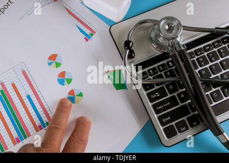 Stethoscope in doctors desk with keyboard pills. Top view with medical statistics Stock Photo