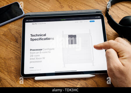 Paris, France - Jun 6, 2019: Man reading on Apple iPad Pro tablet about latest announcement of at Developers Conference WWDC - showing the Mac Pro workstation with CPU processor configuration Stock Photo