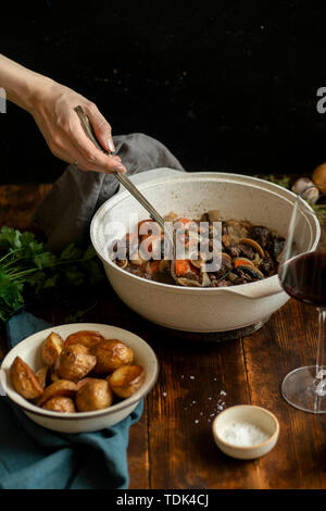 Female hand serving boeuf bourgignon - traditional french beef stew Stock Photo