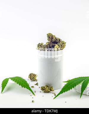 white container with Cannabis flower buds and cannabis leafs isolated on white, medical marijuana concept Stock Photo