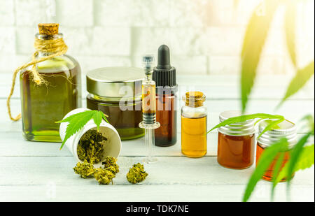 CBD cannabidiol oil glass bottles, pills flower buds and Cannabis leafs on bright wooden table Stock Photo