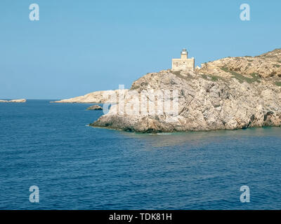 sailing past the lighthouse in ormos harbor on the island of ios, greece Stock Photo