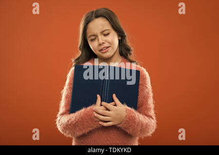 Sad ending story. Girl hold book read story over orange background. Child enjoy reading book. Book store concept. Wonderful free childrens books available to read. Childrens literature. Stock Photo