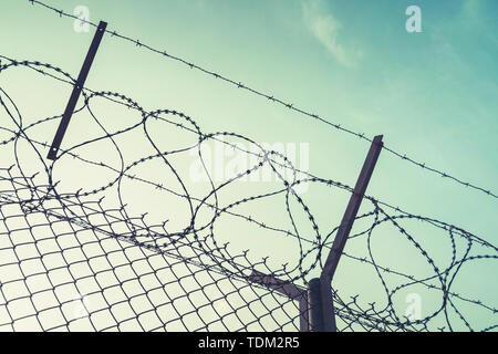 barbed wire steel wall against immigations. Wall with barbed wire on the border of 2 countries. Private or closed military zone against the background Stock Photo