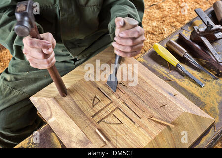 wood chisel carpenter tool hammer in hand working wooden background Stock Photo