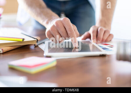 close up hands of man touching tablet, multitasking on screen in an office Stock Photo