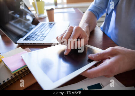 close up hands of man touching tablet, multitasking on screen in an office Stock Photo