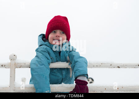 winter portrait of a little boy in red hat and mittens. the baby is smiling