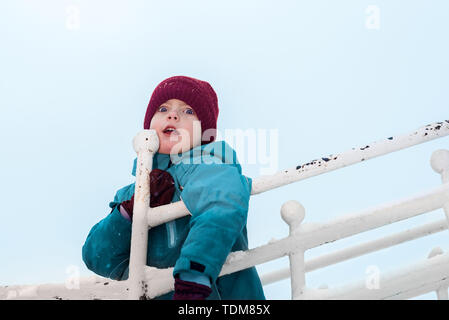 winter portrait of a cute boy in burgundy hat and gloves. emotional child was very surprised Stock Photo