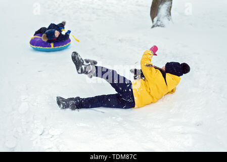 happy children ride a winter slide on a sled. brother and sister play together. kids fell and glide in the snow Stock Photo