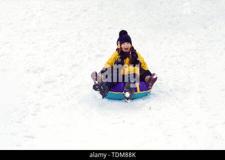 happy children sledding tubing. brother and sister play together in winter. children slide down the hill. kids laugh and scream. emotions Stock Photo